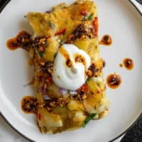 two air fryer enchiladas on a plate garnished with fat free Greek yogurt and salsa macha