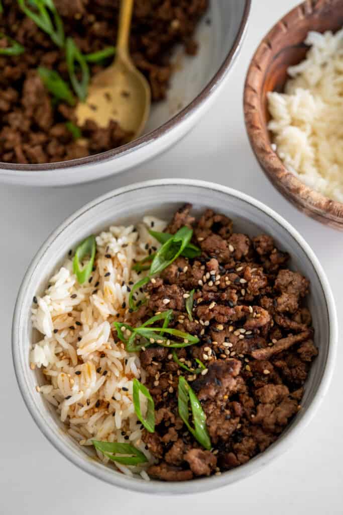 black pepper beef in a bowl with rice garnished with sliced scallions