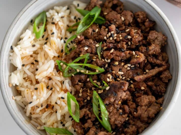 black pepper ground beef and rice in a bowl topped with scallions and sesame seeds