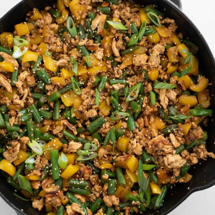 honey sesame ground chicken, bell peppers, and green beans in a cast iron skillet