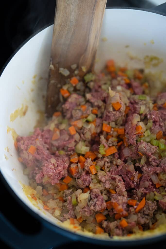 cooking ground beef with vegetables in a Dutch oven