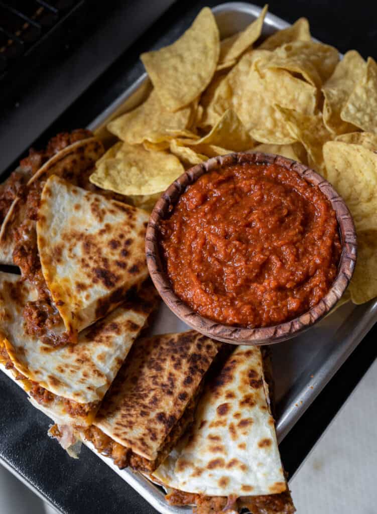 chipotle beef quesadillas on a sheet pan with tortilla chips and chipotle salsa