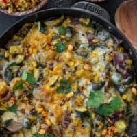 enchilada casserole in a cast iron skillet with refried beans and cauliflower rice sides