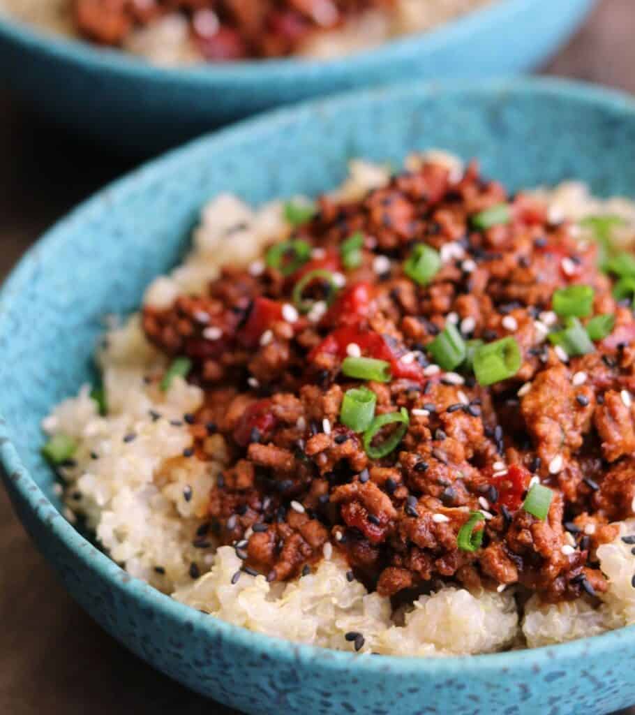 spicy ground beef over quinoa garnished with scallions and sesame seeds