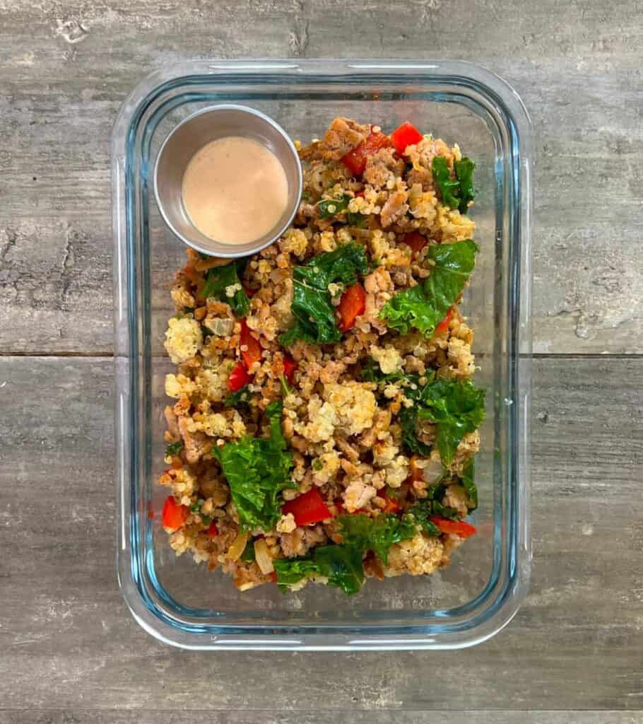ground turkey and kale in a meal prep container with sauce