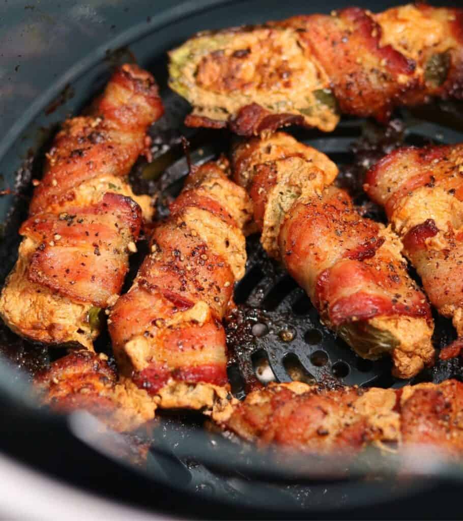 bacon wrapped jalapeño poppers in an air fryer basket
