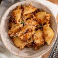 protein mac and cheese in a bowl garnished with parsley and parmigiano reggiano