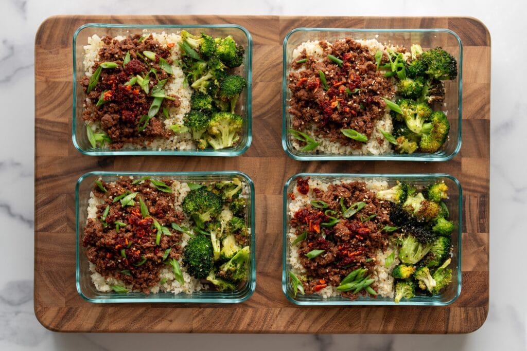 four meal prep containers filled with ground bison, rice, and broccoli