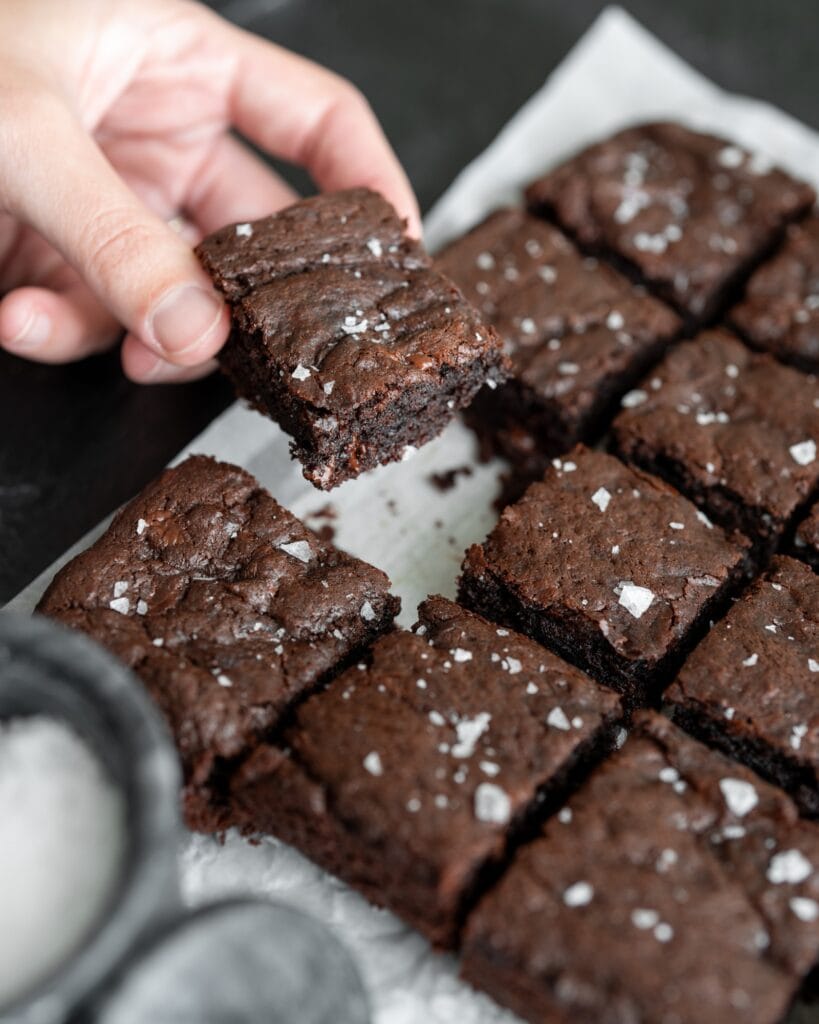 healthy brownies cut into 16 squares on parchment paper and finished with flaky salt