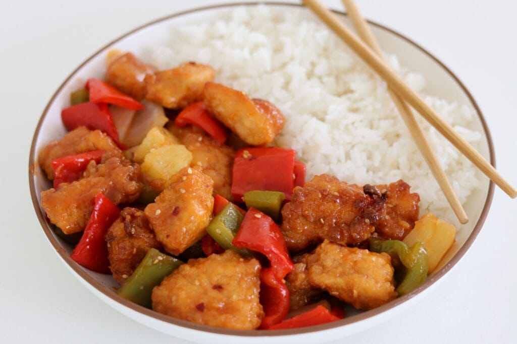 sweet and sour chicken made with Just Bare lightly breaded chicken breast chunks over a bowl of rice