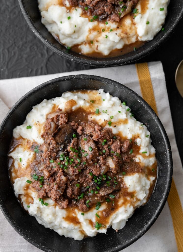 two bowls with ground beef and mashed potatoes topped with chives