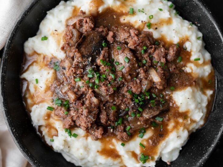 black bowl with mashed potatoes and cauliflower topped with ground beef and mushroom onion gravy