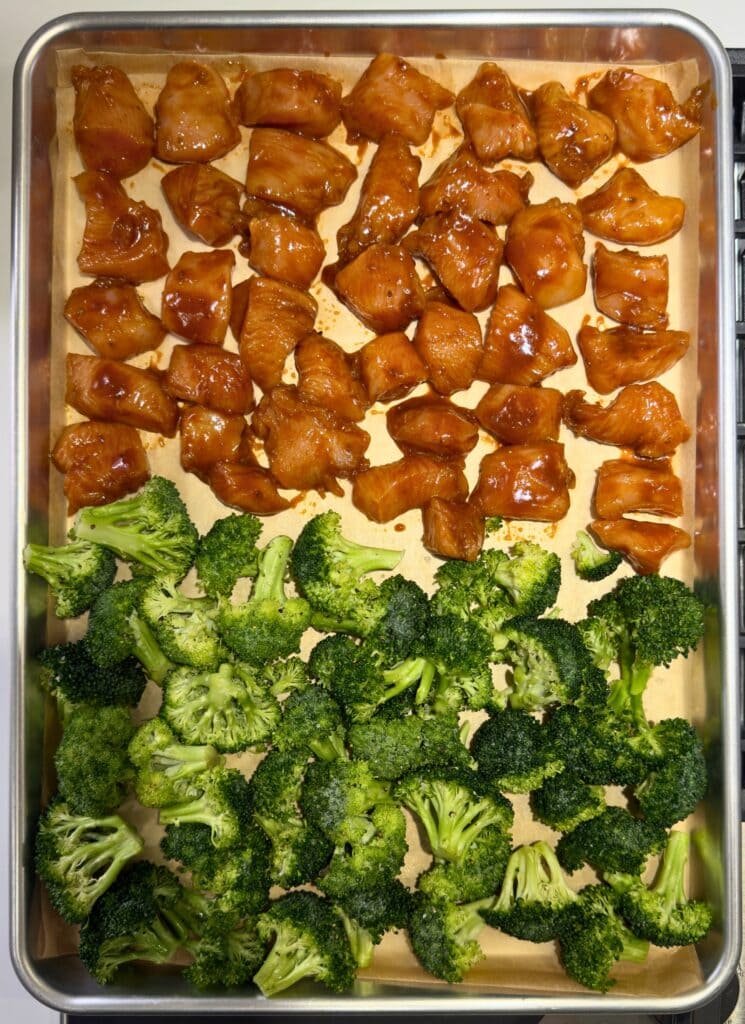 seasoned chicken breast pieces and olive oil tossed broccoli pieces on a sheet pan