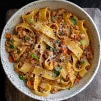 ground turkey bolognese pasta in a bowl garnished with parsley and parmigiano reggiano