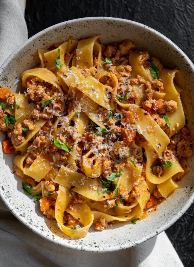 ground turkey bolognese with pappardelle pasta, chopped parsley, and parmigiano reggiano