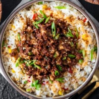 rice and cauliflower rice bowl with Japanese barbecue chicken garnished with scallions, sesame seeds, and yum yum sauce