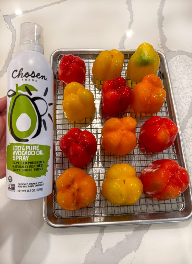 12 bell peppers on a sheet pan with a wire rack sprayed with avocado oil spray before roasting