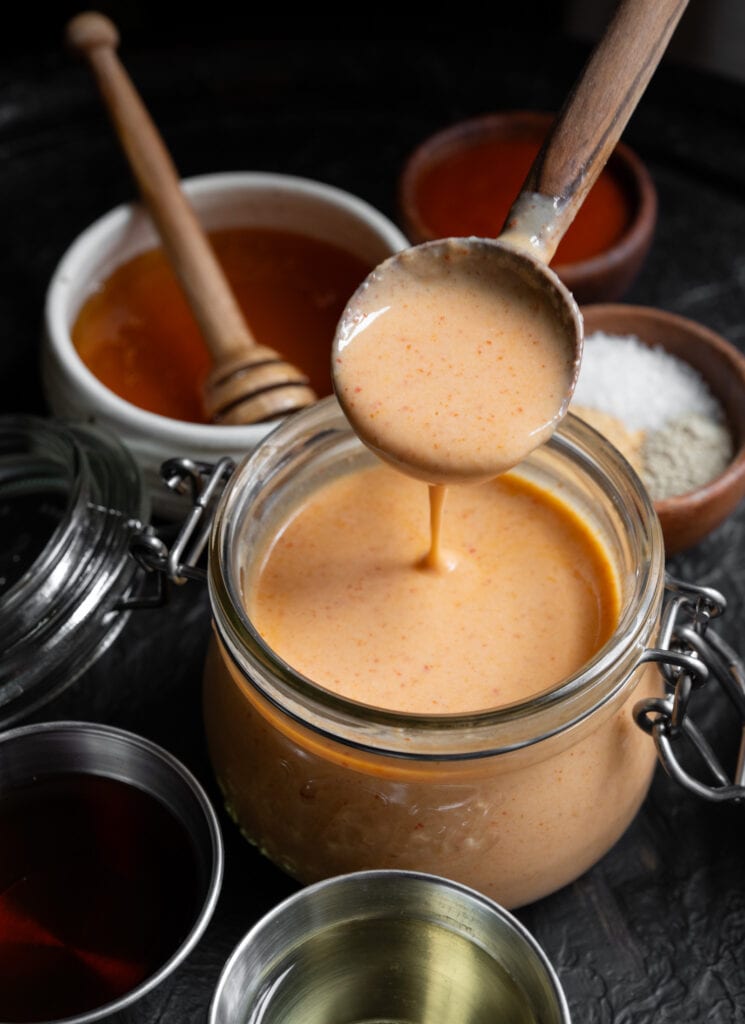 serving yum yum sauce out of a glass jar with a wooden spoon