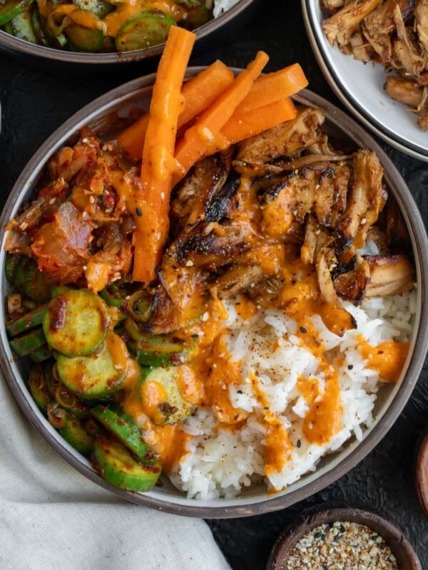Korean BBQ rotisserie chicken bowls with rice, creamy kimchi sauce, kimchi, cucumber kimchi, and pickled carrots