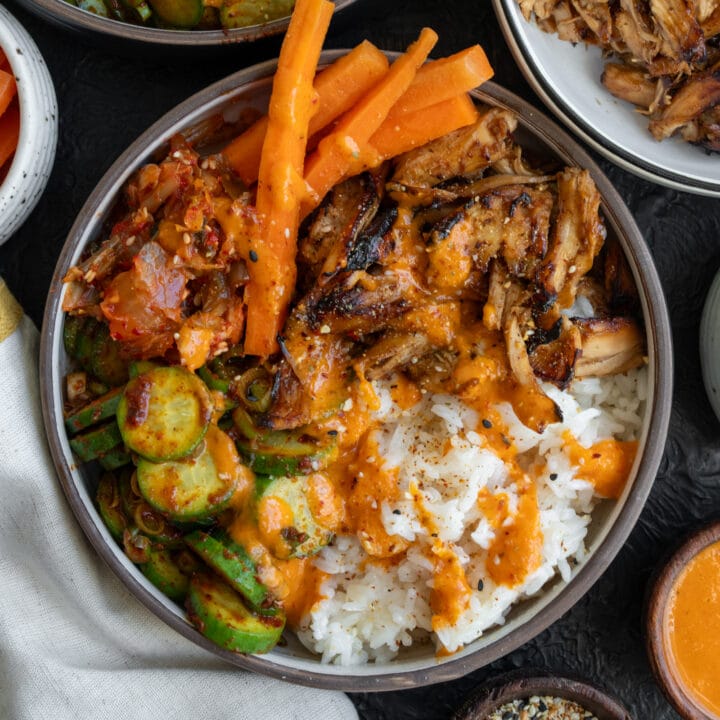 Korean BBQ rotisserie chicken bowls with rice, creamy kimchi sauce, kimchi, cucumber kimchi, and pickled carrots