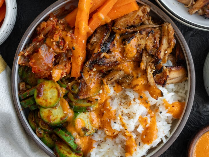 Korean BBQ rotisserie chicken bowls with rice, creamy kimchi sauce, kimchi, cucumber kimchi, and pickled carrots