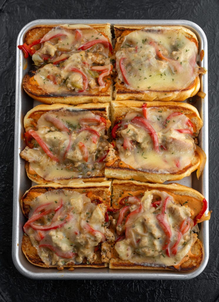 six chipotle chicken cheesesteak sandwiches on a half sheet pan