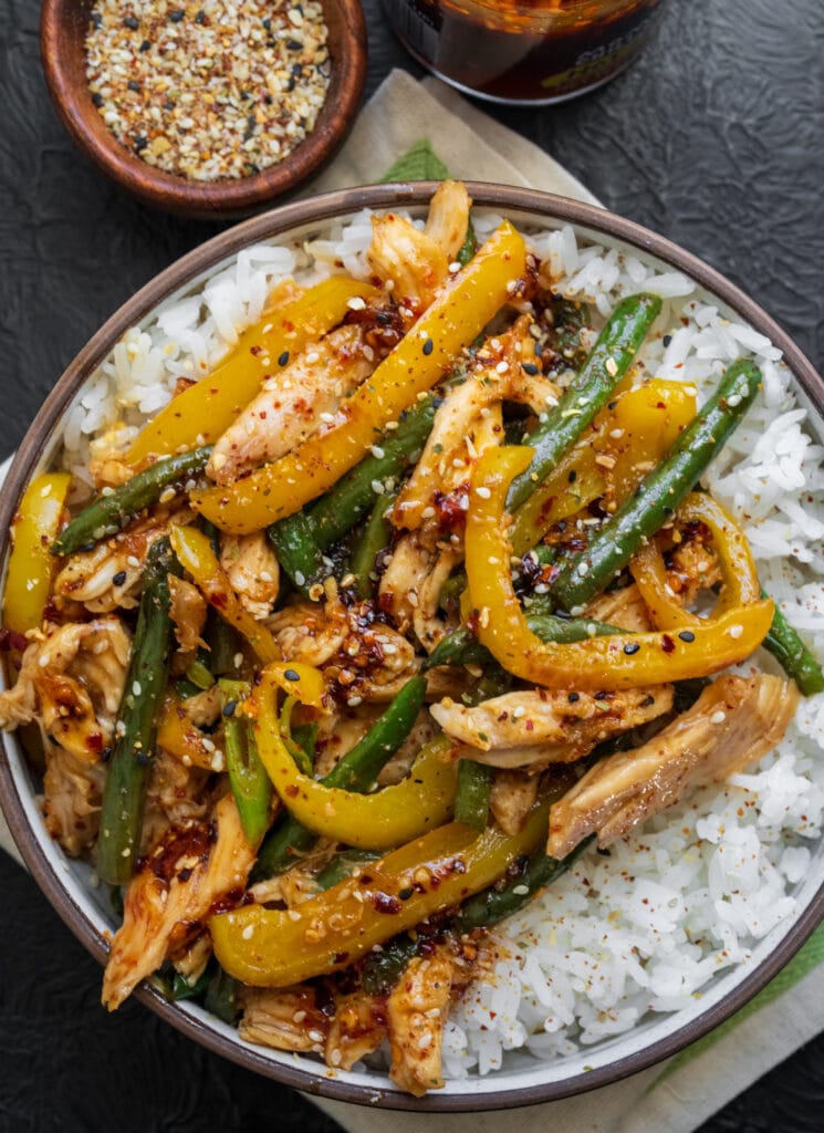 honey sesame rotisserie chicken stir fry over rice with toasted sesame seeds, scallions, and hot honey chili crunch