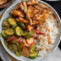 sweet chili rotisserie chicken in a bowl with half calorie rice and cucumber crunch salad