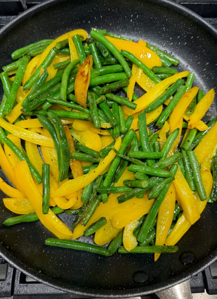 stir fried green beans and yellow bell peppers in a nonstick skillet