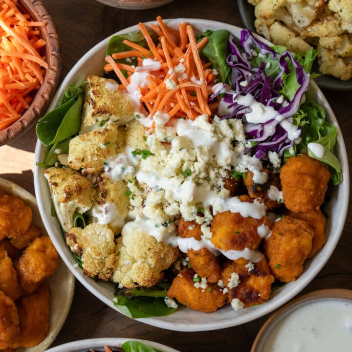 buffalo chicken and roasted cauliflower bowls with mixed greens, carrots, cabbage, blue cheese, and Greek yogurt ranch