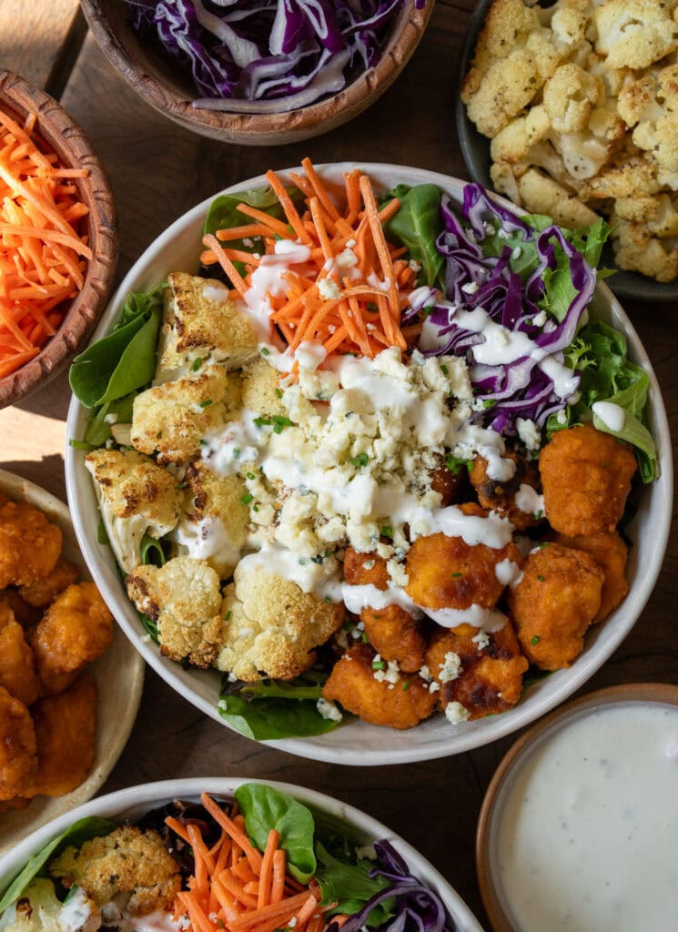 buffalo chicken and roasted cauliflower bowls with mixed greens, carrots, cabbage, blue cheese, and Greek yogurt ranch