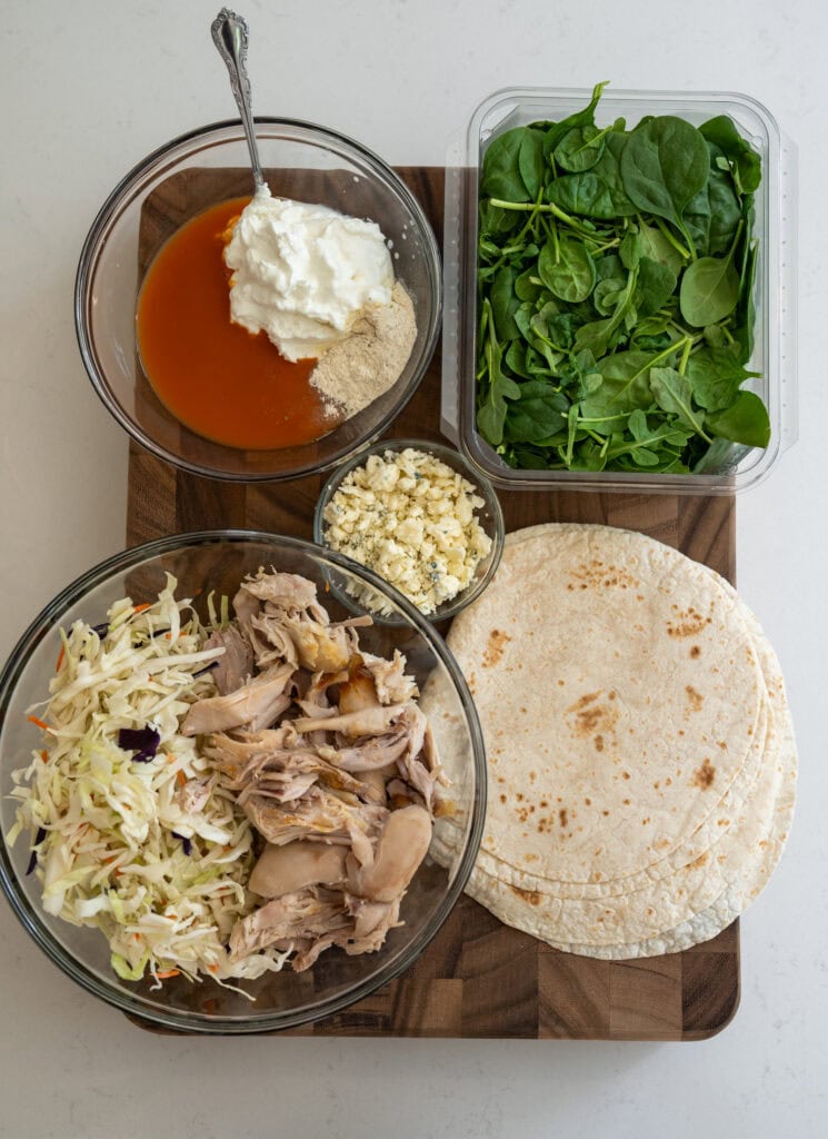 pulled rotisserie chicken, coleslaw mix, Greek yogurt with buffalo sauce and ranch seasoning, blue cheese crumbles, spinach and arugula, and tortillas