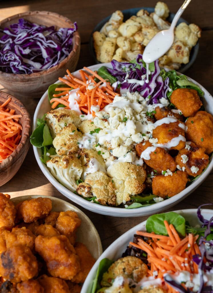 Greek yogurt ranch drizzled over crispy buffalo chicken and roasted cauliflower bowls