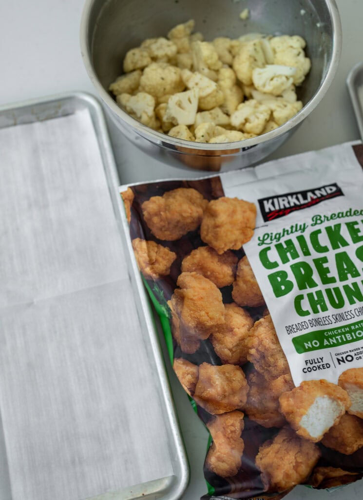 Kirkland lightly breaded chicken breast chunks with cauliflower florets in a mixing bowl