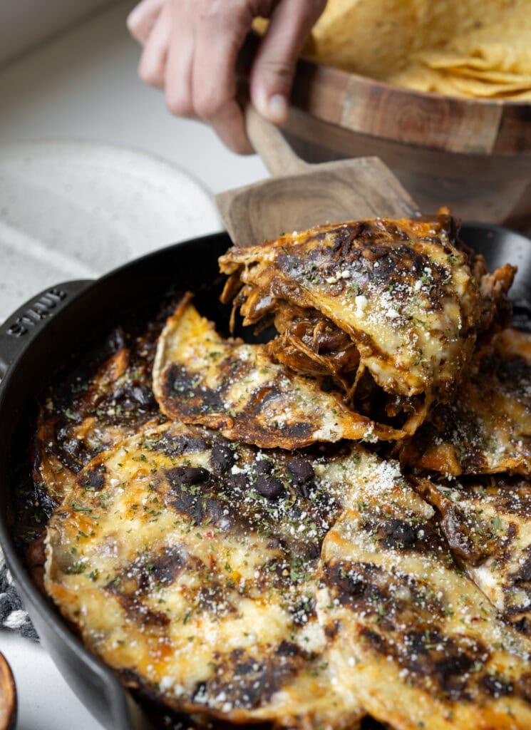 serving a slice of mole chicken enchilada casserole out of a skillet