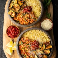 two ground chicken and zucchini orzo bowls with calabrian chiles, lemon wedges, grated parmigiano reggiano, and basil