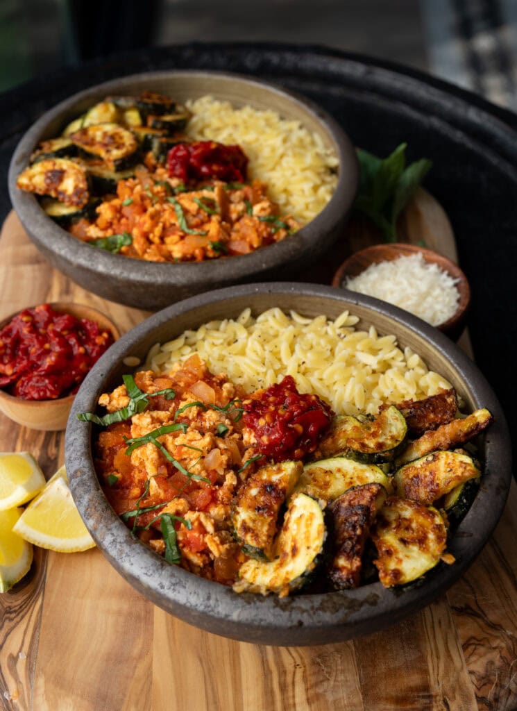 two Italian chicken and orzo bowls on a wooden serving board