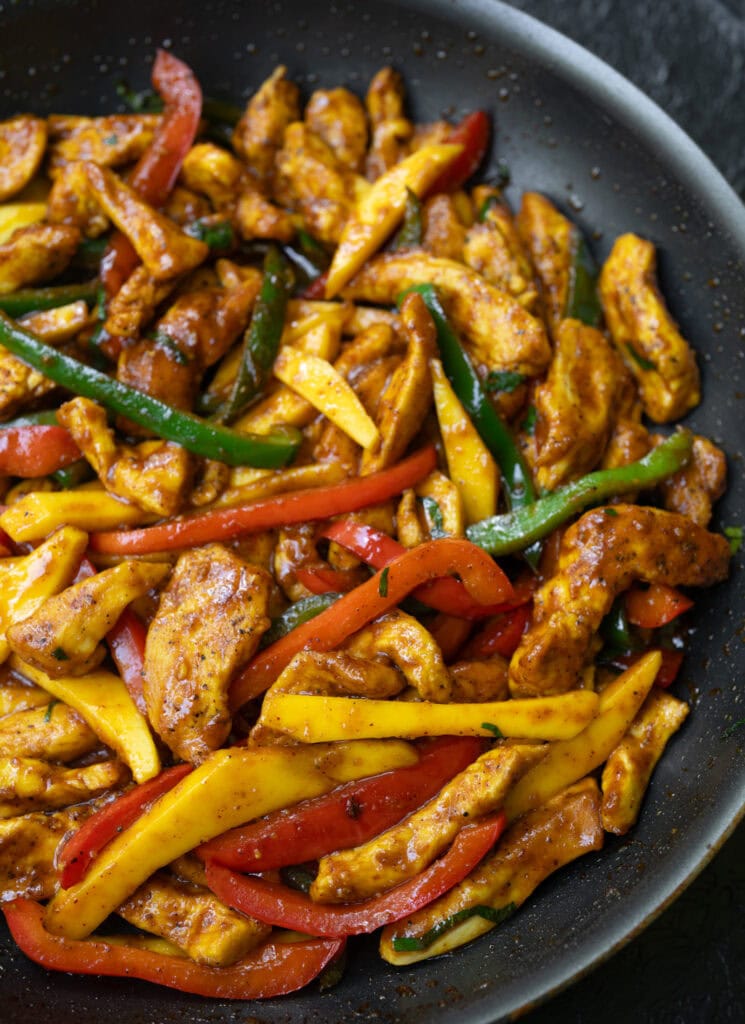 Thai chili chicken breast and peppers with mango in a skillet