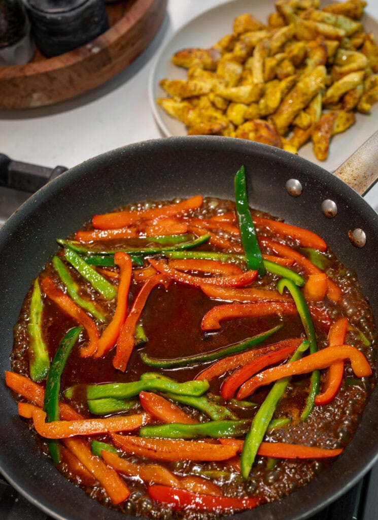 cooking peppers with the Thai chili sauce in the skillet after transferring the cooked chicken to a plate