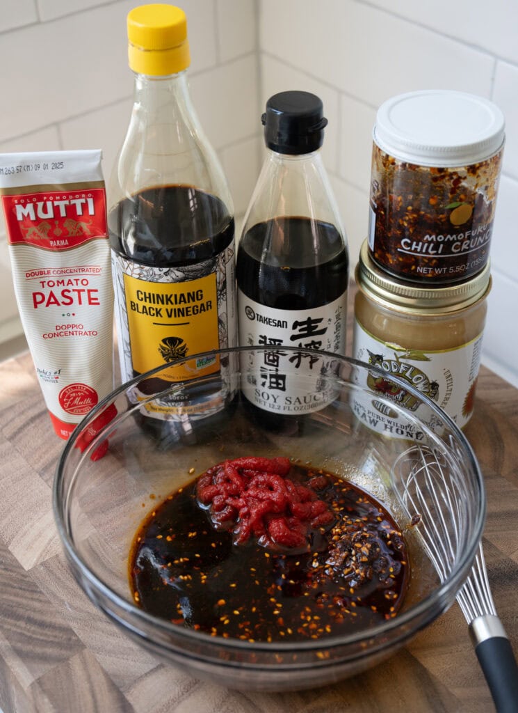 tomato paste, black vinegar, soy sauce, chili crunch, and honey in a mixing bowl
