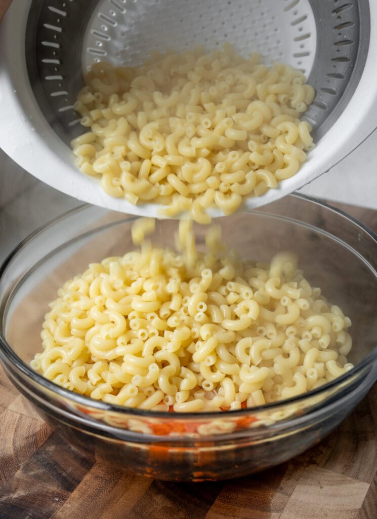 adding cooked macaroni to grated carrots and onion