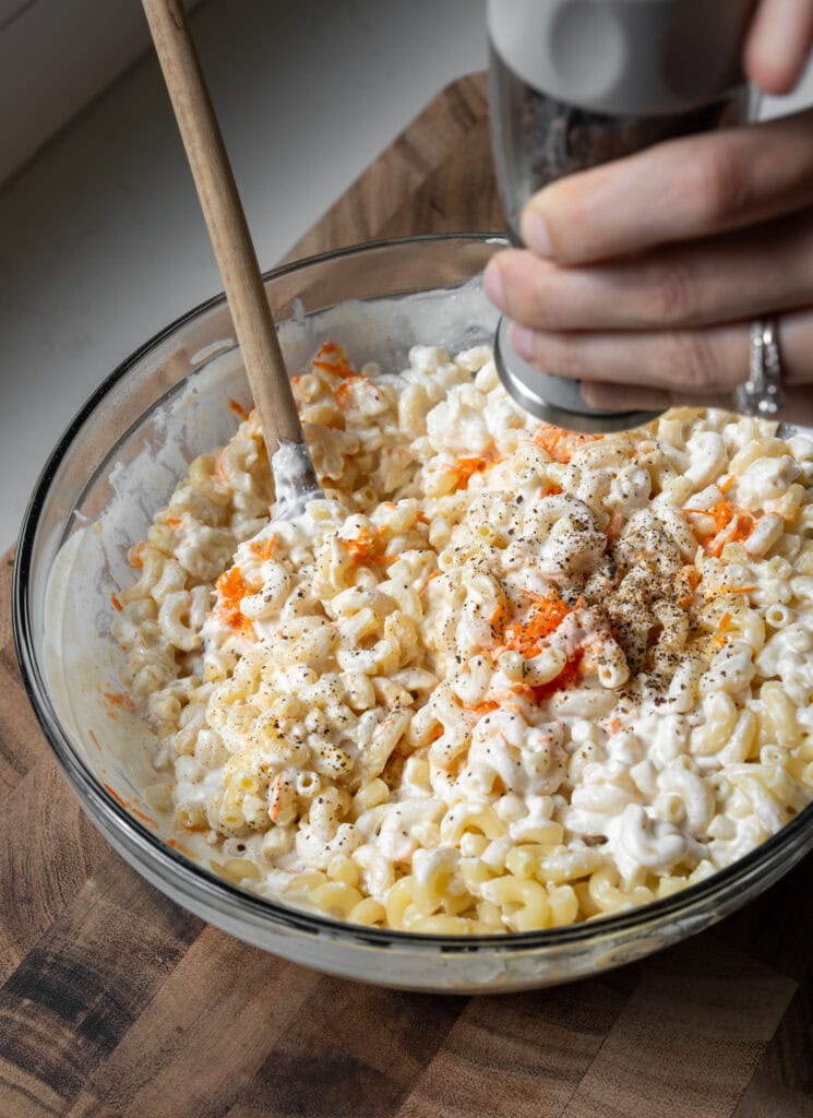 adding cracked black pepper to cooked macaroni and blended cottage cheese sauce