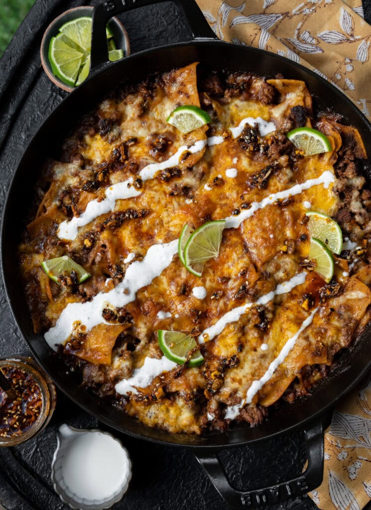 ground beef birria casserole with lime wedges and Mexican crema