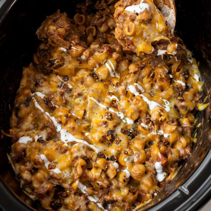 serving pulled beef chili mac from a Crockpot with a wooden spoon