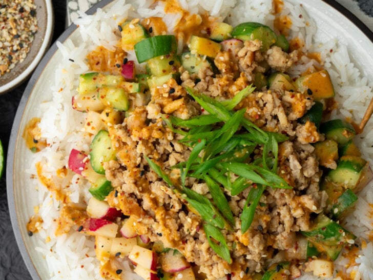 sesame ginger chicken crumbles on a plate with jasmine rice and cucumber crunch salad