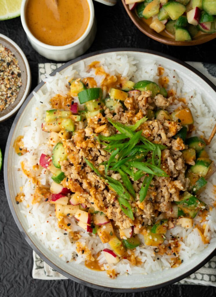 sesame ginger chicken crumbles on a plate with jasmine rice and cucumber crunch salad