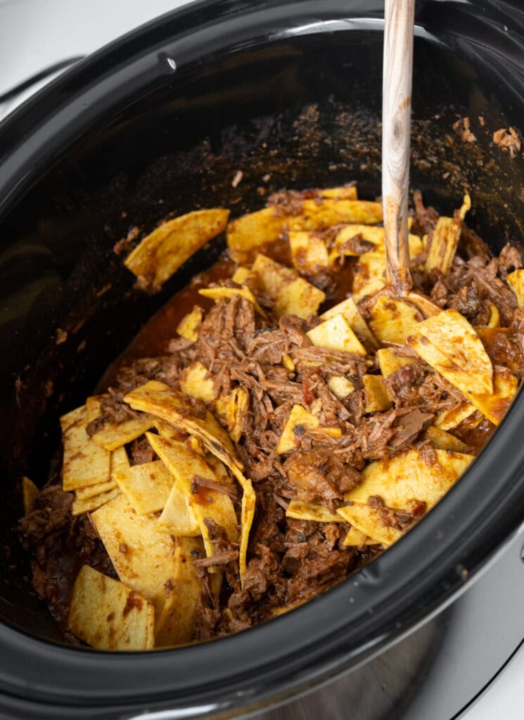 folding chopped corn tortillas into shredded top round roast in a Crockpot