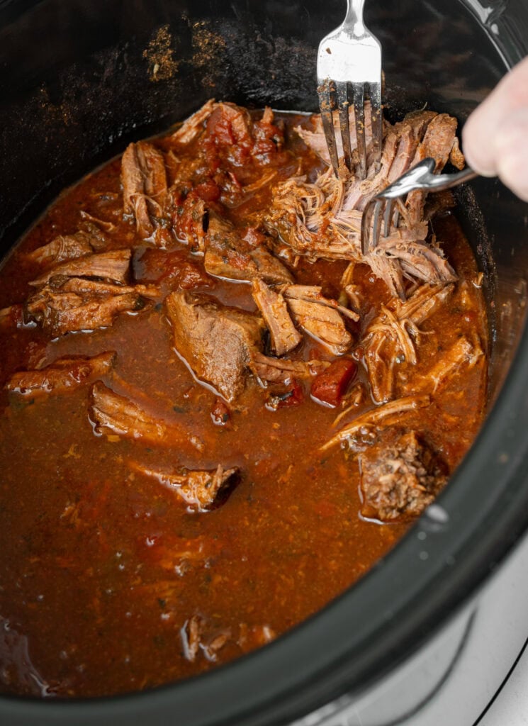 shredding beef in a Crockpot with two forks