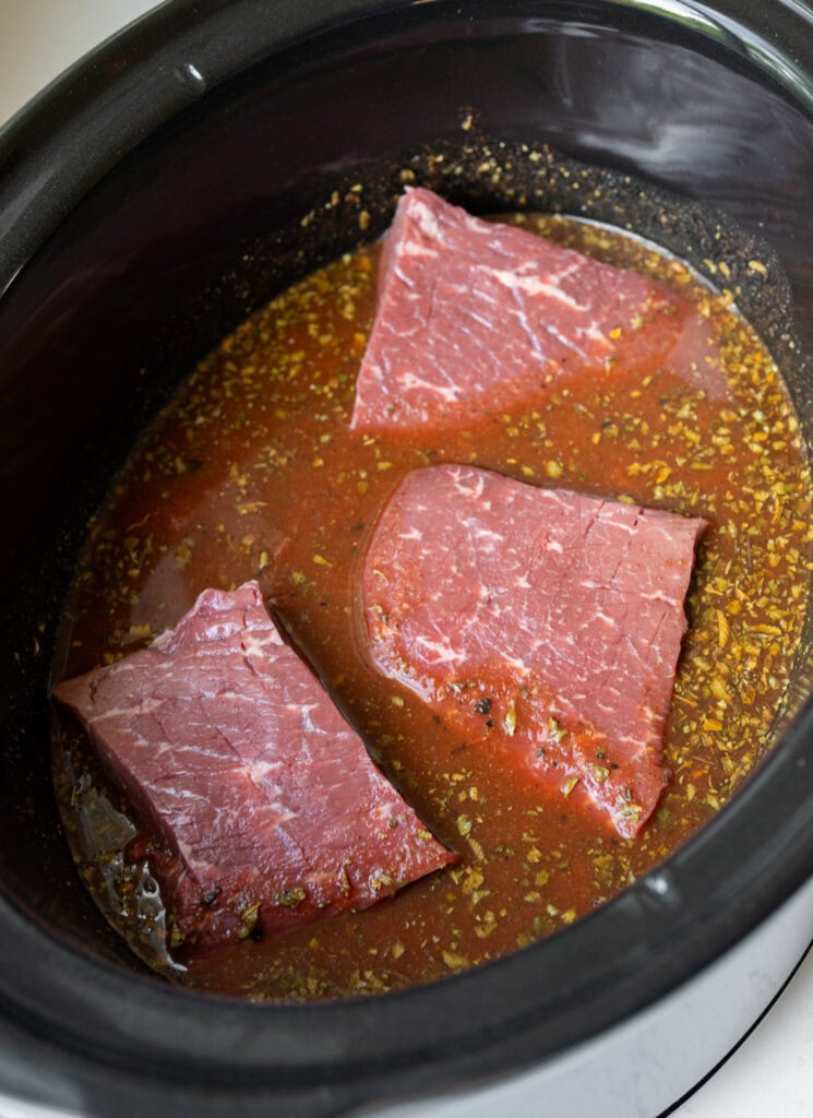 chunks of top round beef in a Crockpot with fire roasted crushed tomatoes, chicken broth, and spices