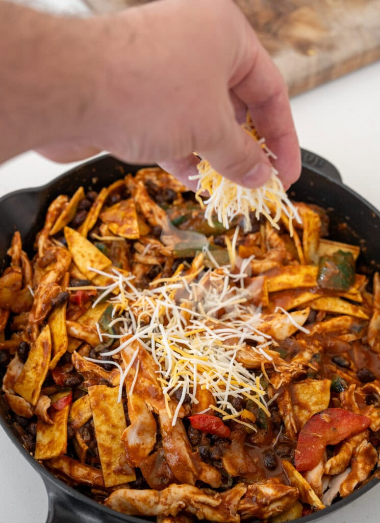 sprinkling cheese over chicken fajita casserole before baking